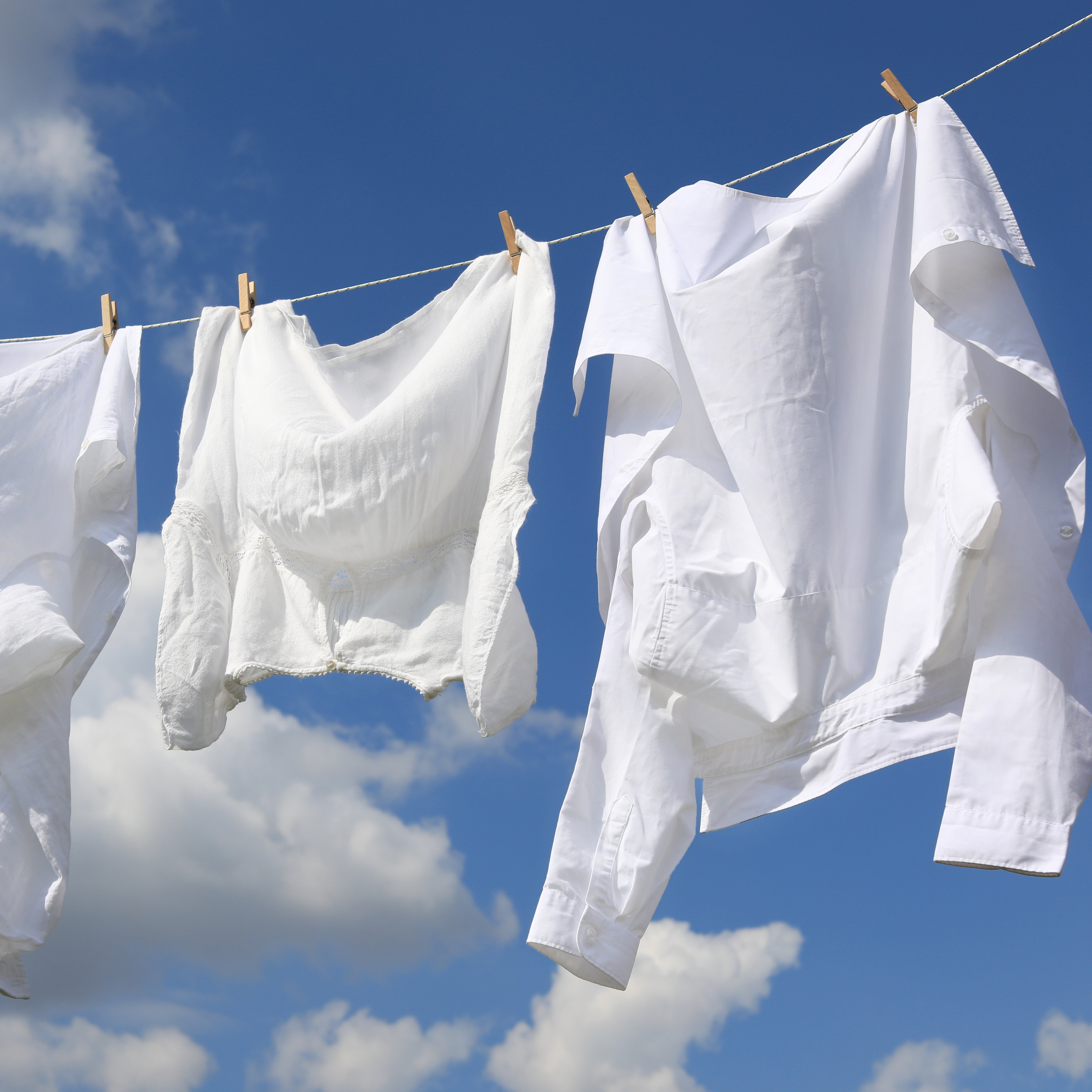 three linen shirts hanging to dry on a clothesline