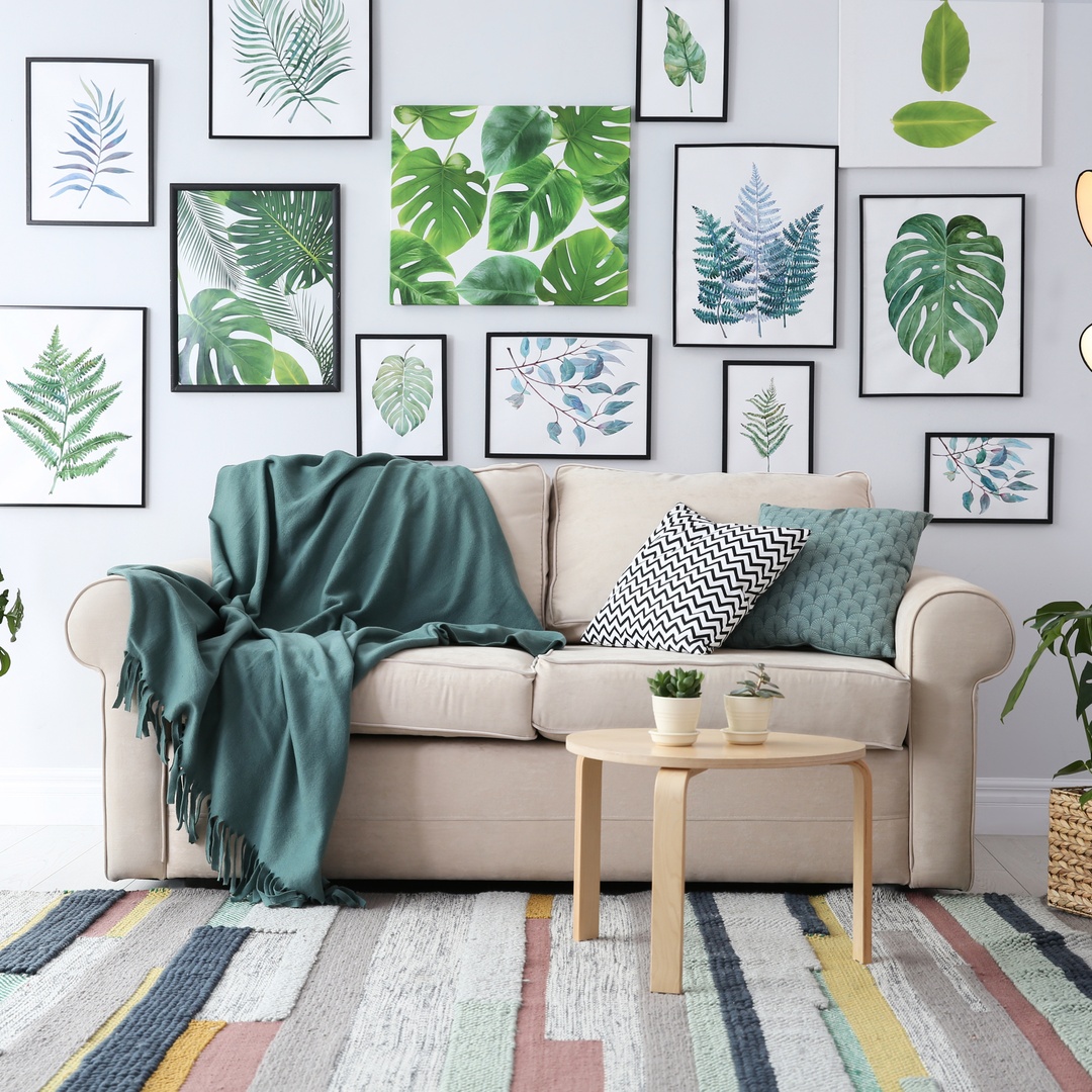 A gallery wall featuring plant art prints in a living room with a sofa, rug, and other matching decor.