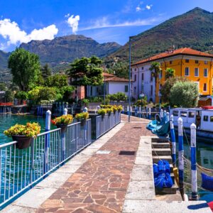 A picturesque town sits on the edge of a large body of water. A pathway over the water leads to the town.