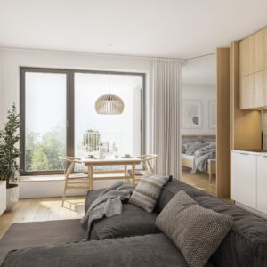 A small apartment with an oversized gray sectional in the center of the living space. A dining set sits by the window.