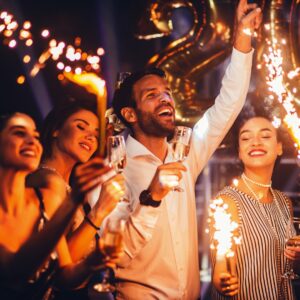 A group of friends cheering and enjoying the moment as they hold champagne and sparklers for the New Year.