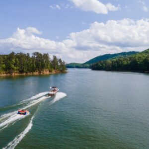 A boat pulling a wakeboarder through clean waters while other passengers enjoy the open view.