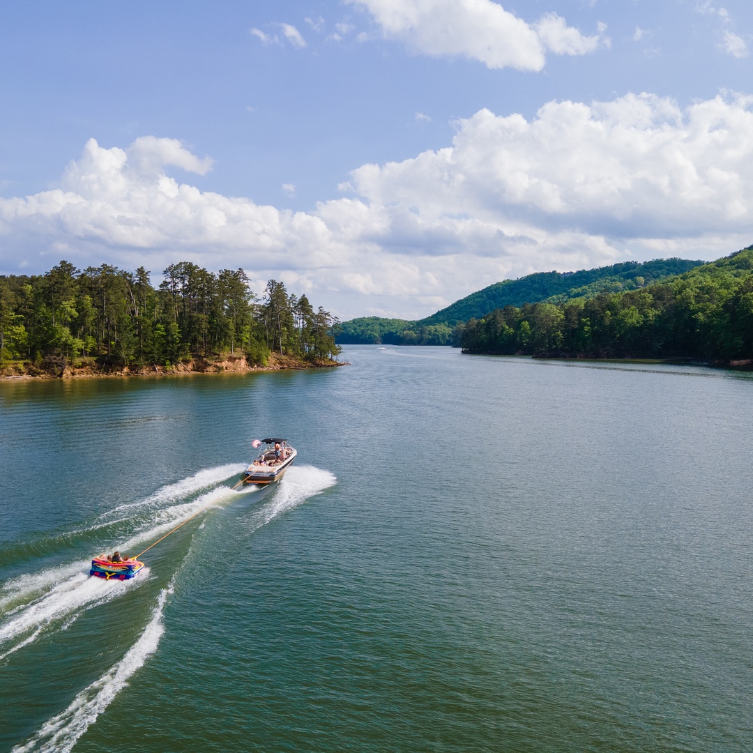 A boat pulling a wakeboarder through clean waters while other passengers enjoy the open view.