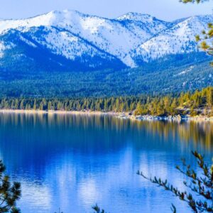 A beautiful view of Lake Tahoe, showcasing the snowy caps on the mountains and dense forests around the lake.