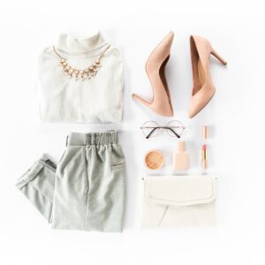 A shirt, shorts, high heels, sunglasses, cosmetics, and a purse sit arranged neatly inside an open suitcase.