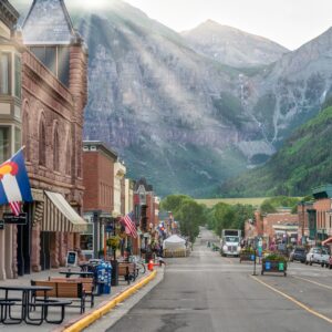 Several buildings sit on each side of Main Street in Telluride, Colorado. The mountains are visible in the background.