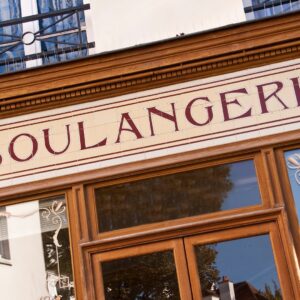 A bakery storefront featuring a large Boulangerie sign above wooden-framed glass doors and decorative windows.