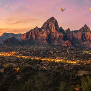 Four hot air balloons are floating above the red rock formations of Sedona, Arizona, as the sun rises.